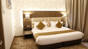 Ein Hotelzimmer mit einem großen Bett, einem hölzernen Kopfteil, zwei Nachttischen mit Lampen und einer Wand mit Muster.