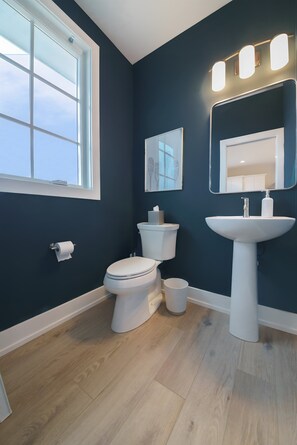 A bathroom with a white toilet, a white sink, and a window.