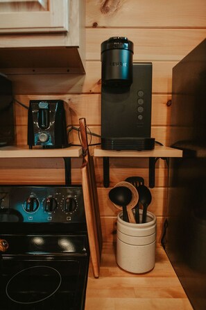 Une cuisine équipée d’une machine à café, d’une cuisinière et d’ustensiles de cuisine.