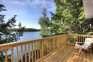 Une terrasse en bois offrant une vue sur un lac et des arbres.