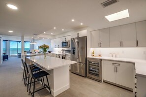 A modern kitchen with a central island, stainless steel appliances, and a view to the living area.
