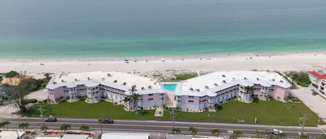 Un hôtel situé en bord de mer, doté d’une piscine, de plusieurs balcons et d’une route menant à la plage.