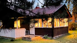 Una baita con tetto spiovente, un portico e una finestra con luce calda all'interno.