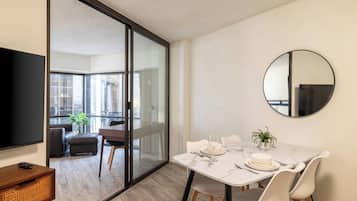 A modern dining area with a glass partition, a round mirror, and a dining table set for two.