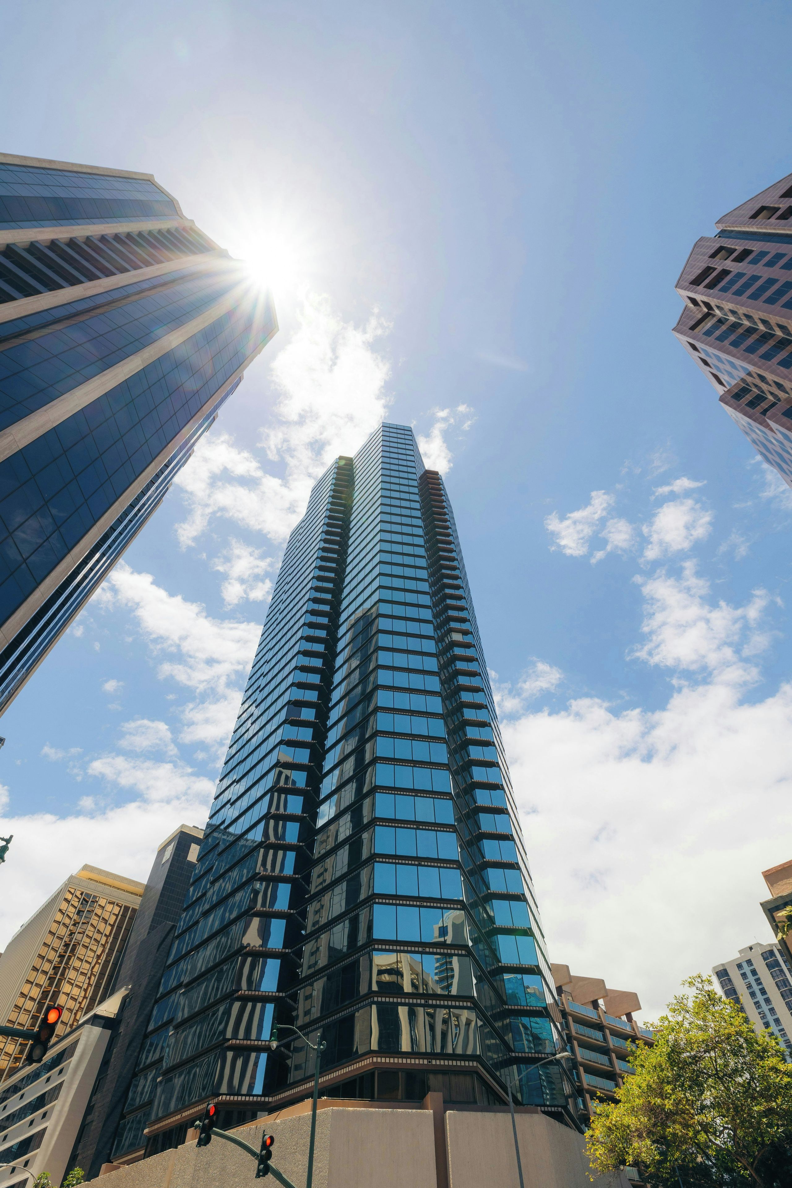A tall, modern skyscraper with a glass facade, surrounded by other buildings.