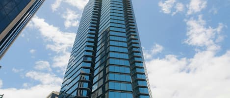 Un rascacielos alto y moderno con fachada de vidrio, rodeado de otros edificios.