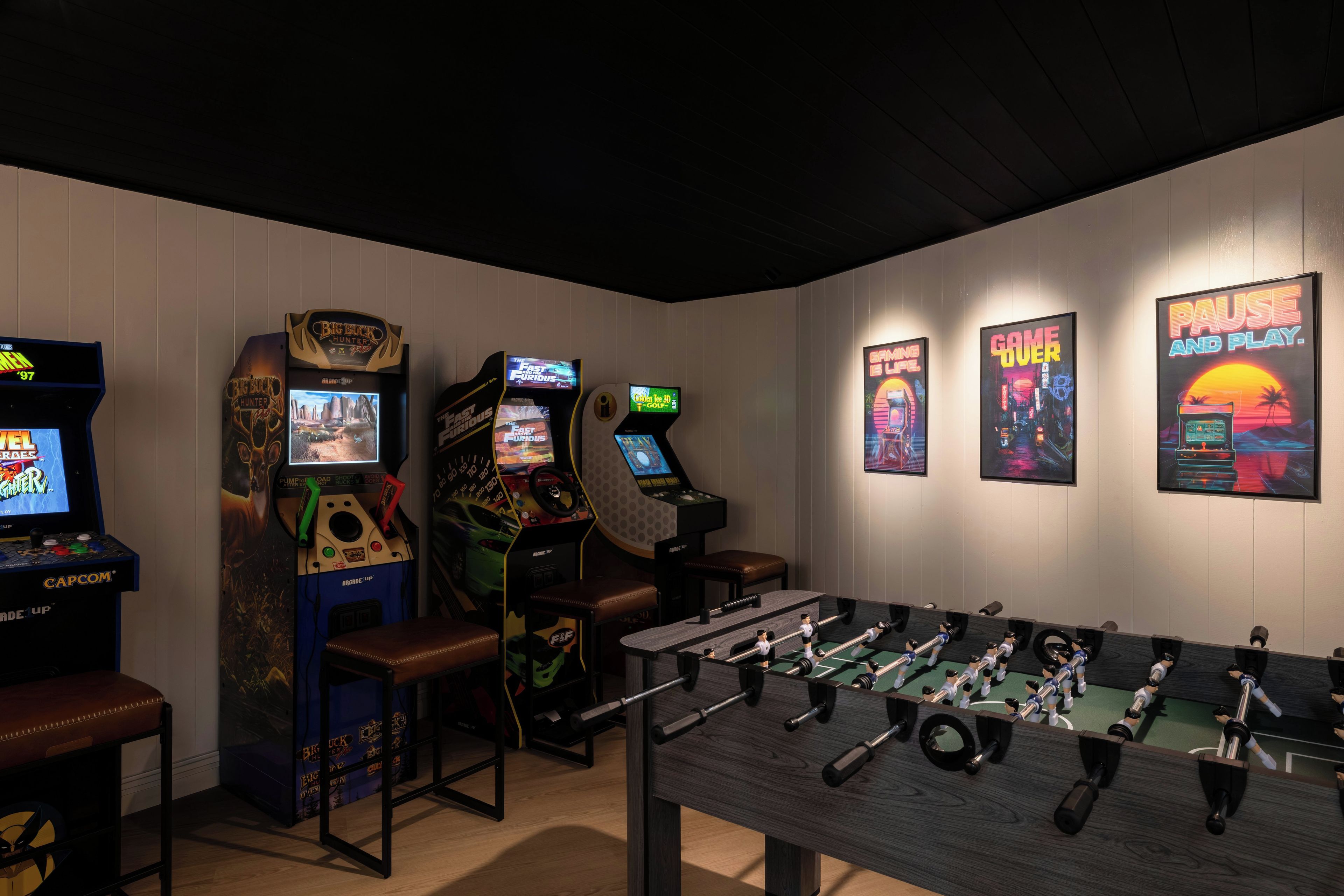 Una habitación con máquinas de videojuegos, una mesa de futbolín y carteles en la pared.