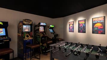 Una habitación con máquinas de videojuegos, una mesa de futbolín y carteles en la pared.