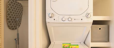 A front view of a white washing machine with control knobs and two boxes of Gain Original detergent on the door.