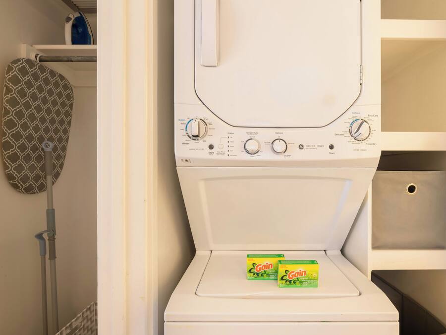 Vista frontal de uma máquina de lavar branca, com botões de controle e duas caixas de detergente Gain Original na porta.