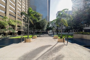 A plaza with a fountain, surrounded by tall buildings and trees.