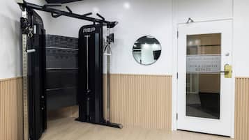 A gym with a pull-up bar, a wall-mounted mirror, and a door with a sign.
