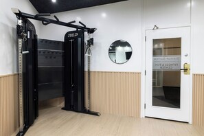 A gym with a pull-up bar, a wall-mounted mirror, and a door with a sign. - Bishop Suites Downtown Honolulu (Honolulu)
