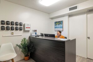 A reception desk with a computer, a plant, and a sign for Bishop Suites. - Bishop Suites Downtown Honolulu (Honolulu)