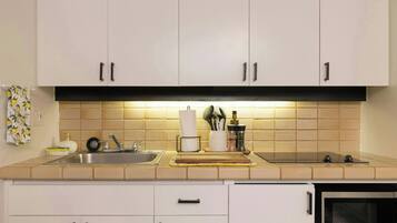 A kitchen with white cabinets, a stainless steel sink, and a microwave.