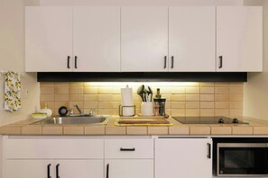 A kitchen with white cabinets, a stainless steel sink, and a microwave. - Bishop Suites Downtown Honolulu (Honolulu)