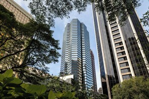 Un immeuble moderne de grande hauteur, doté d’une façade en verre, entouré d’arbres verdoyants.