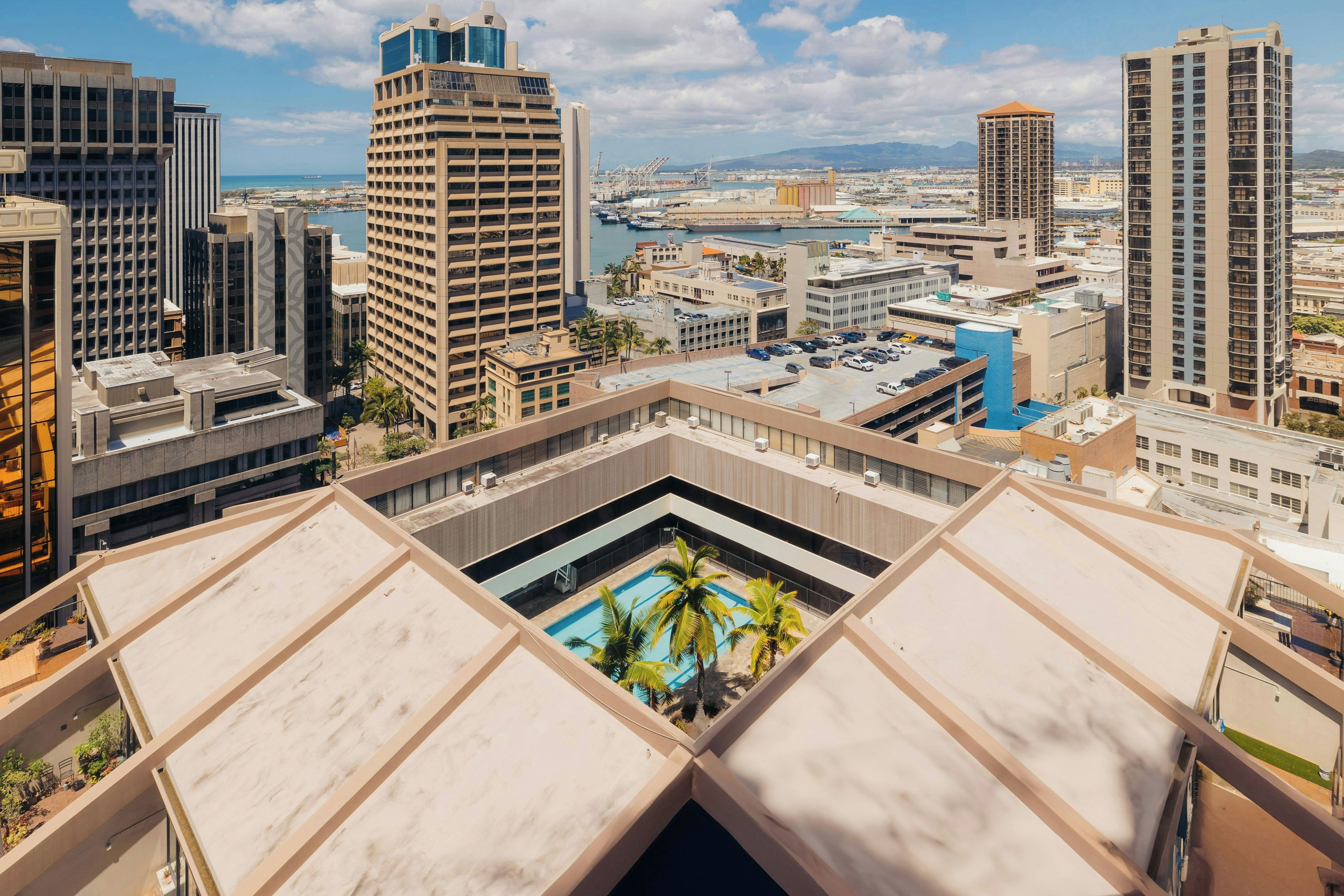 A high-rise building with a rooftop pool and a view of the cityscape.