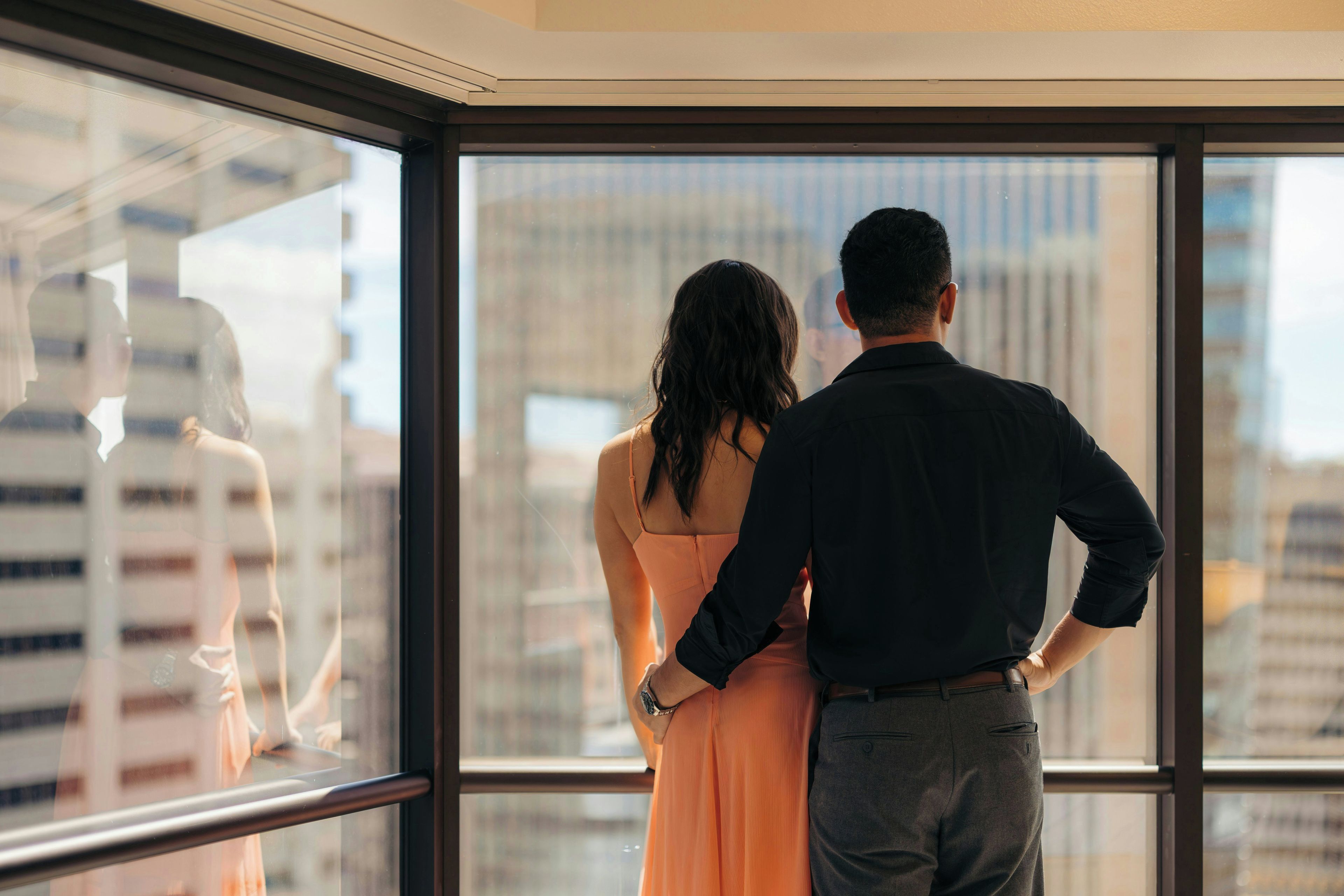 A couple standing by a window with a cityscape view.