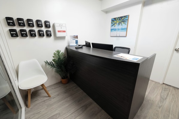 A reception desk with a sign, a plant, and a white chair. - Bishop Suites Downtown Honolulu (Honolulu)