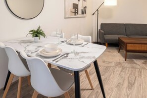 Un comedor con una mesa de mármol, sillas blancas y un sofá gris.