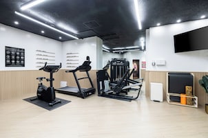 A fitness center with treadmills, a weight machine, and a wall with exercise area names.