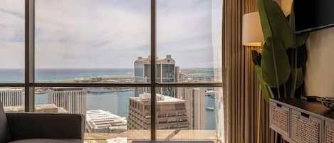 A hotel room with a large window offering a view of the city skyline and a body of water.