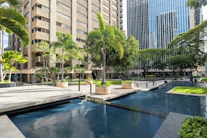 A modern building with a pool area, surrounded by greenery and a clear sky. - Bishop Suites Downtown Honolulu (Honolulu)
