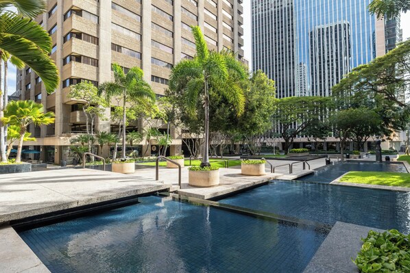 A modern building with a pool area, surrounded by greenery and a clear sky. - Bishop Suites Downtown Honolulu (Honolulu)