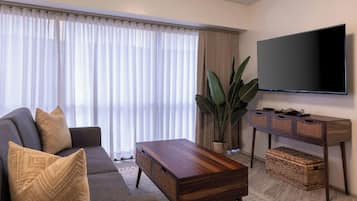 A modern living room with a sofa, coffee table, TV, and a large plant.