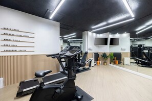 A gym with exercise equipment, a wall with names, and a large mirror. - Bishop Suites Downtown Honolulu (Honolulu)