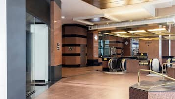 A modern elevator area with a marble floor, a glass elevator door, and a sign indicating 'Lobby'.