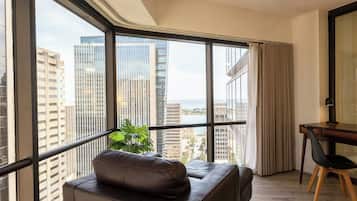 A modern room with a leather sofa, a dining table with chairs, and large windows offering a city view.