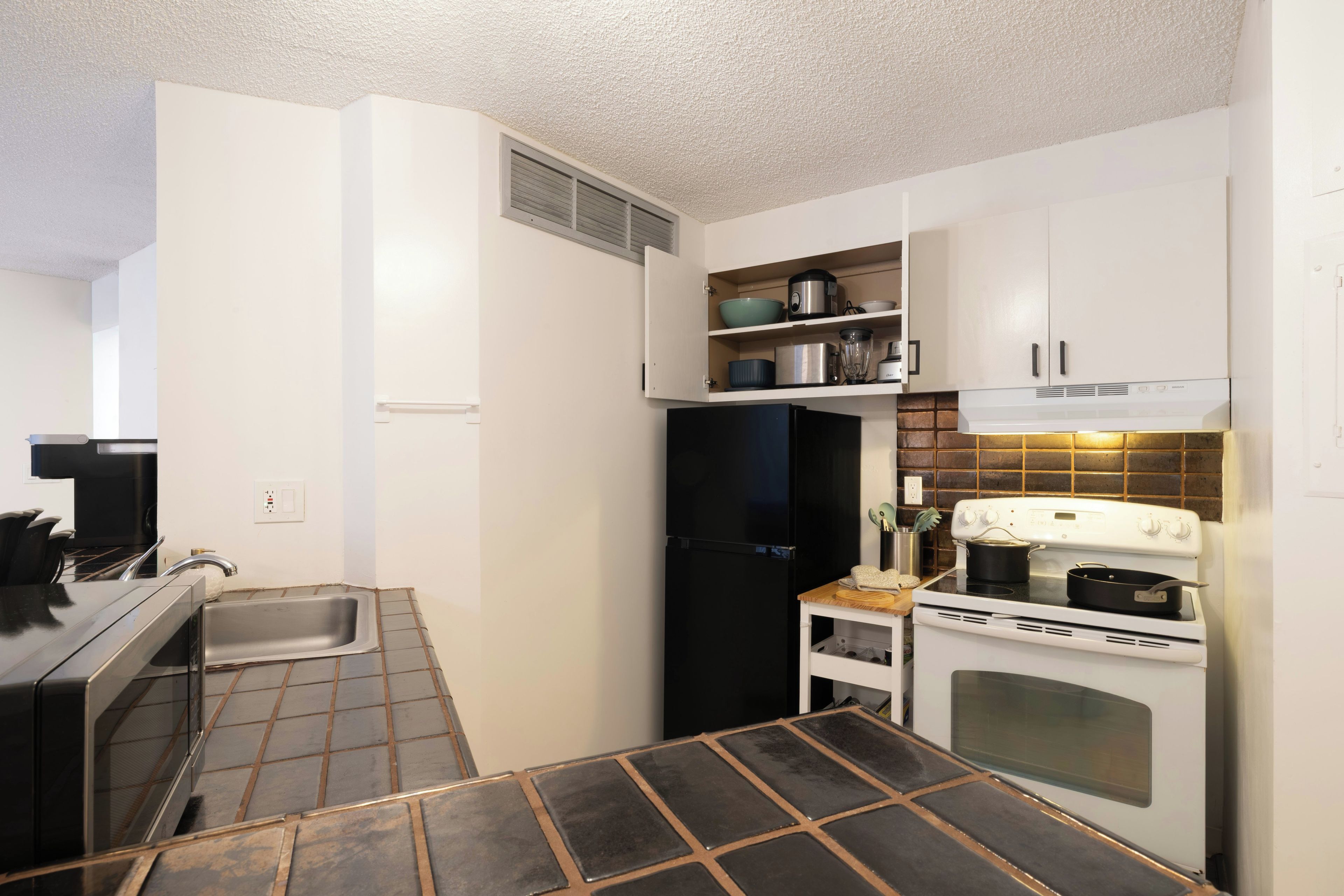 Una cocina compacta con horno integrado, estufa, lavamanos y encimera con tabla de cortar.