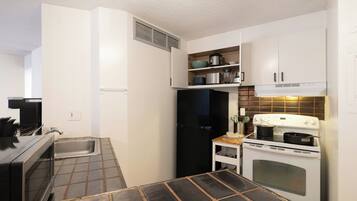Una cocina compacta con horno integrado, estufa, lavamanos y encimera con tabla de cortar.