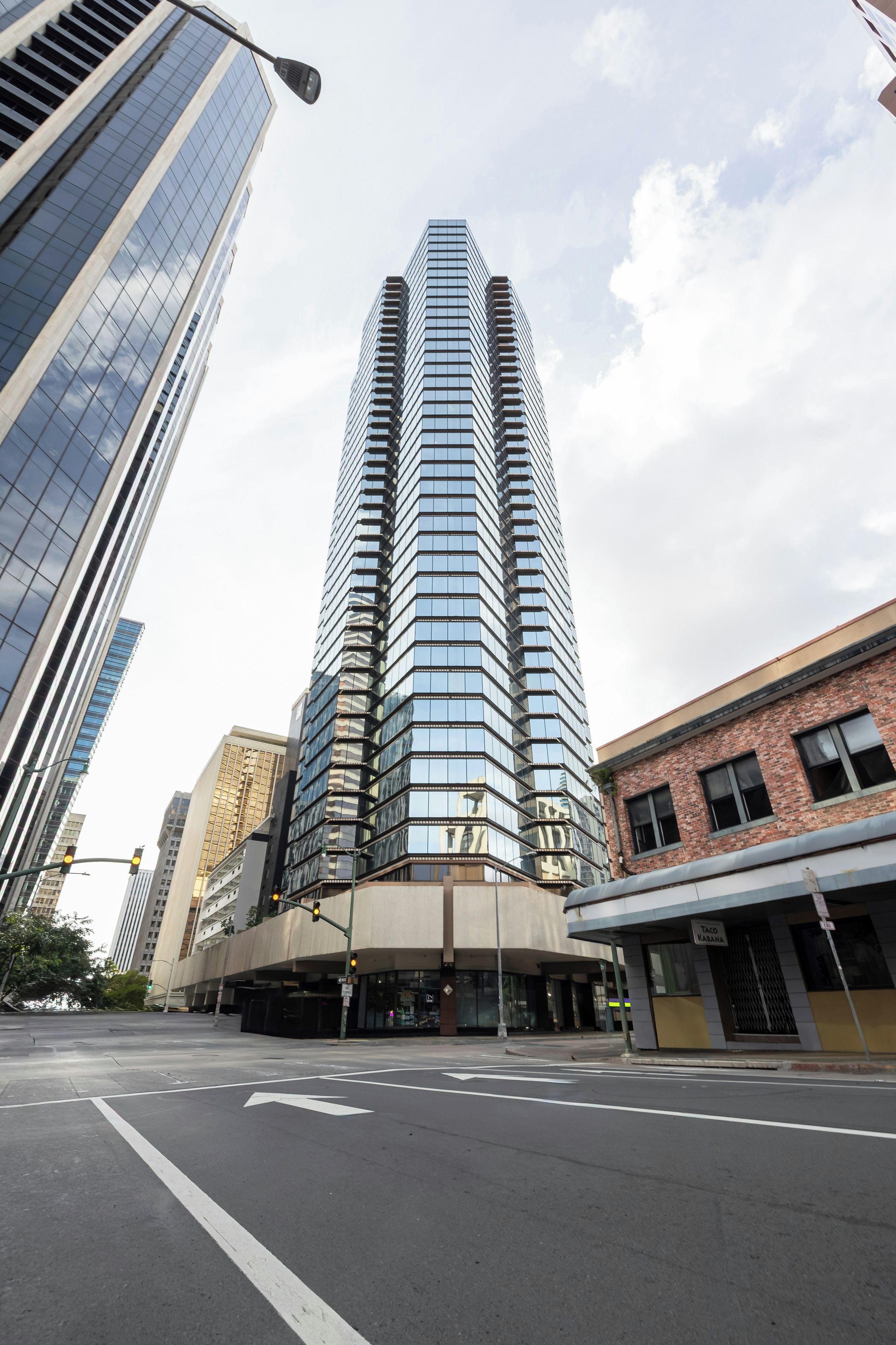 Un moderno edificio de gran altura con fachada de vidrio, situado en una intersección urbana.