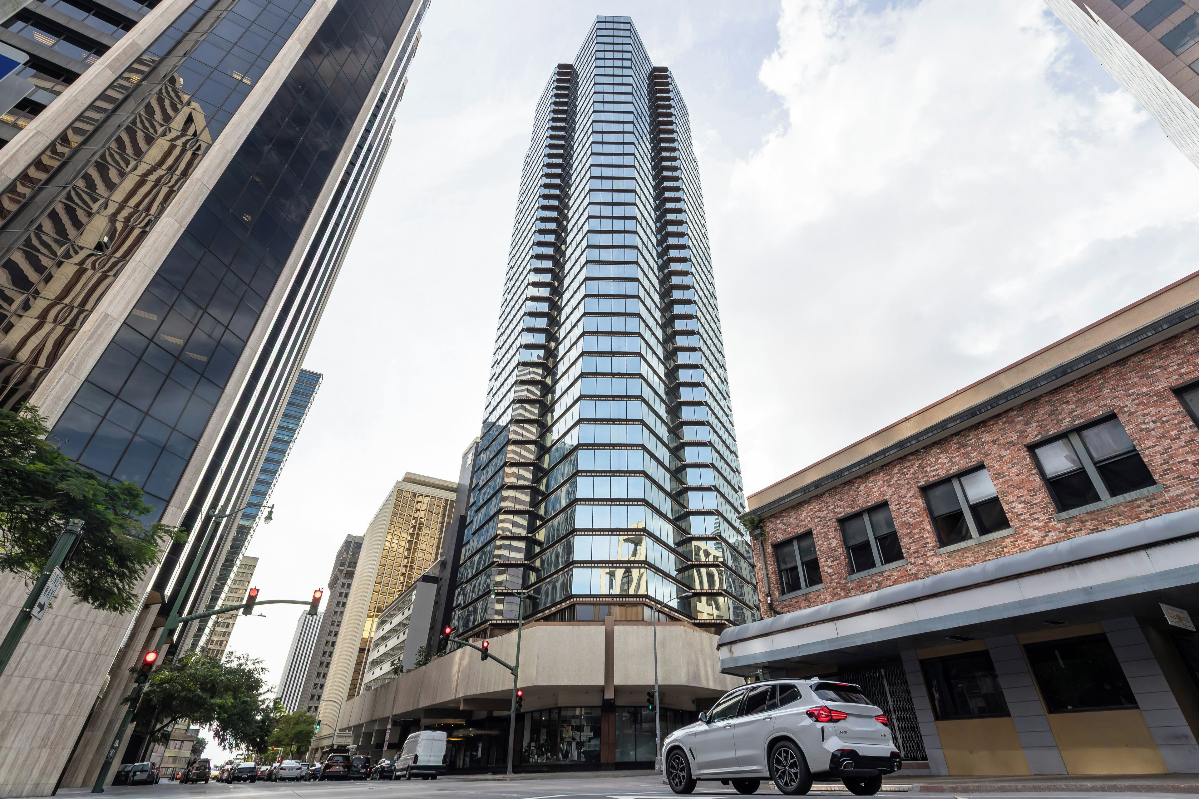 A tall, modern skyscraper with a glass facade, surrounded by urban buildings.