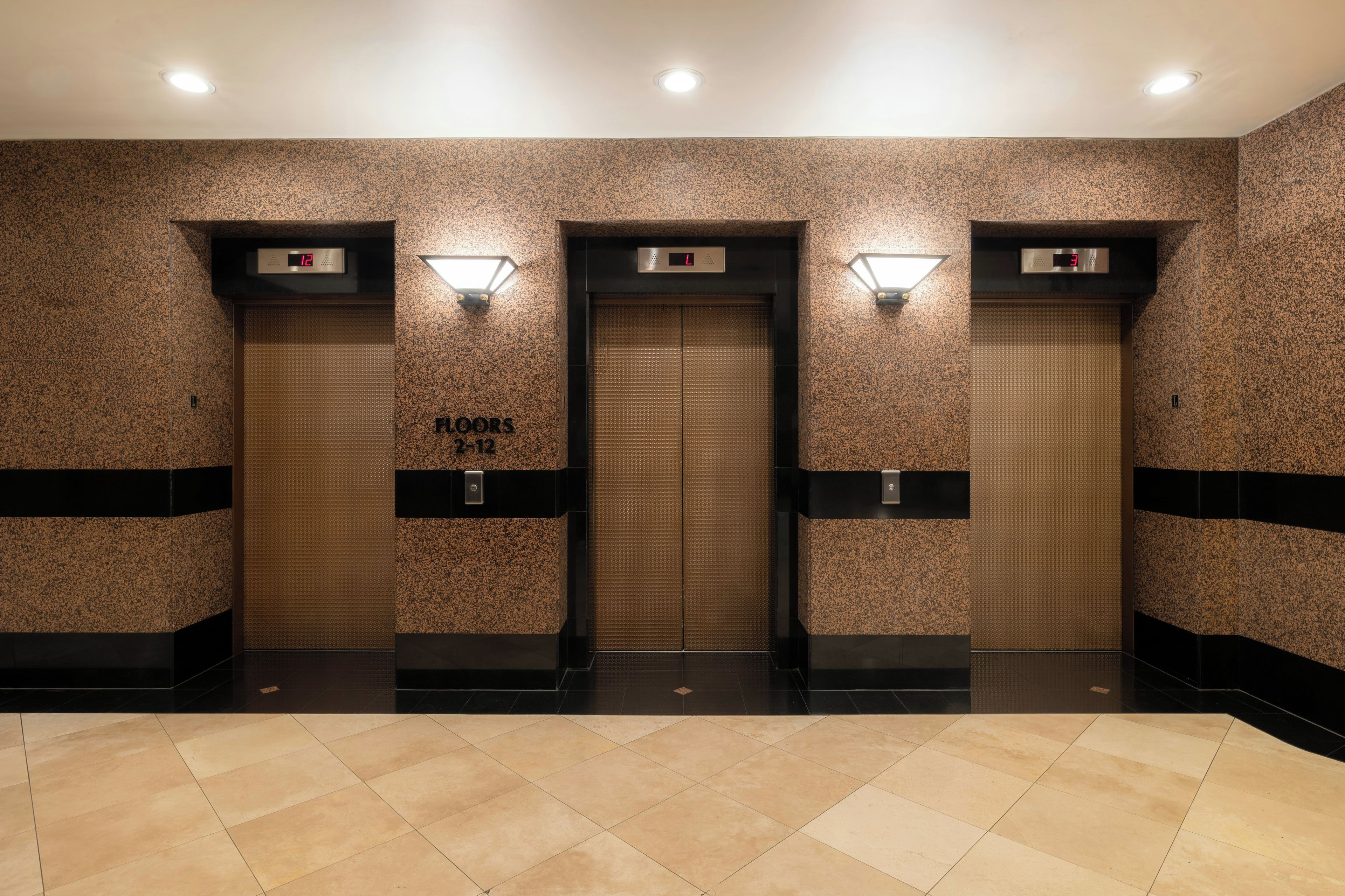 A modern elevator area with three elevators, each with a digital display above the doors.