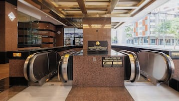 Zona interna con due scale mobili, un cartello per l'Executive Centre e vista sull'esterno.