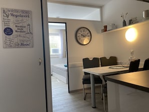 A modern kitchen with a dining area, featuring a clock, a light fixture, and a wall-mounted sign with text.