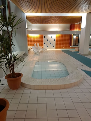 A pool area with a central water feature, lounge chairs, and potted plants.