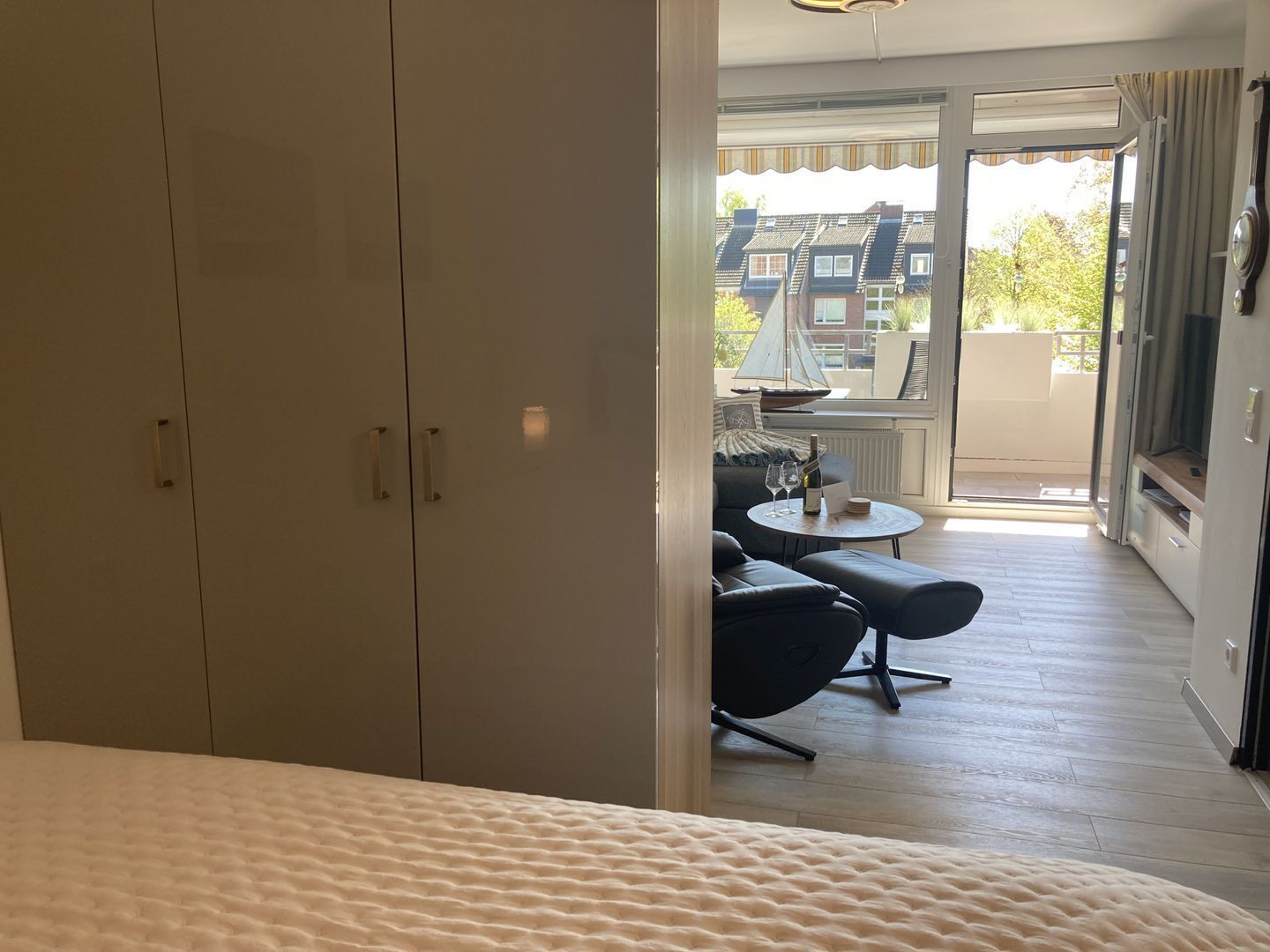 Une chambre à coucher comprenant un lit, une armoire et un balcon avec une table et des chaises.
