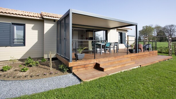 A modern house with a wooden deck, outdoor seating, and a garden area.