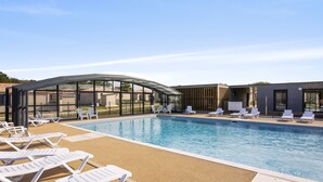 A swimming pool with lounge chairs and a covered area.
