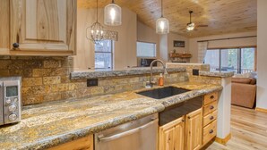 A kitchen with granite countertops, wooden cabinets, stainless steel appliances, and pendant lighting. - Torreon Cardinal Landing Cabin With Party Garage (Show Low)