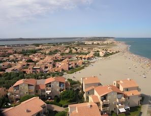 A coastal residential area with terraced houses, a sandy beach, and a clear view of the sea.