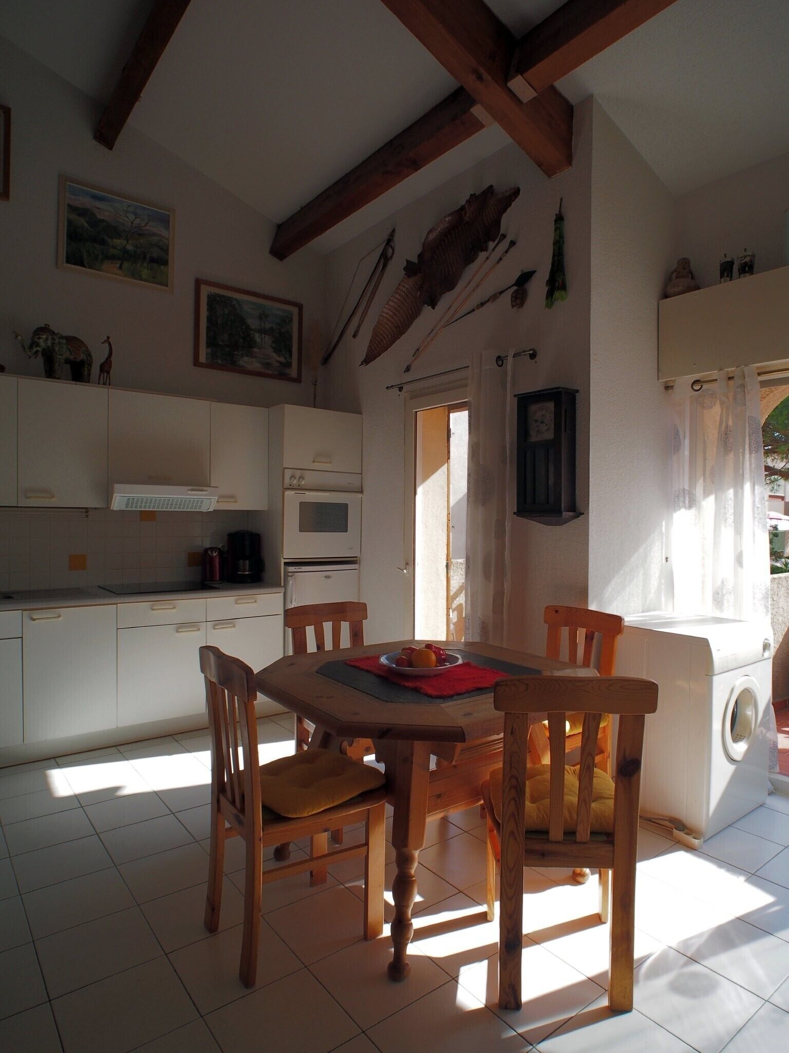 A kitchen with a dining table, chairs, and a washing machine.