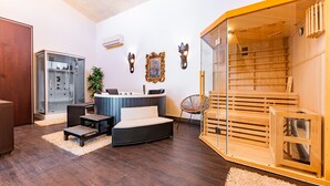 Ein modernes Wohnzimmer mit einer Glassauna, einem Holzkabinett und einer Sitzecke mit Kissen.