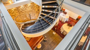 Eine Wendeltreppe mit Steinwand, ein runder Tisch mit einer Vase und ein gemustertes Teppich.