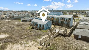 A coastal residential area with houses connected by wooden walkways. - 5381- Sol-T-Escape - Wake to Ocean Views | Oceanfront KDH Condo (Kill Devil Hills)
